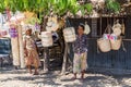 Two local elderly native East Timorese women, street vending traditional wicker baskets hanging on ropes, near Dili, Timor-Leste.