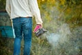 Diligent adult man beekeeper work with bee smoker in his apiary on bee farm