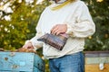 Diligent adult man beekeeper work with bee smoker in his apiary on bee farm