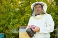 Diligent adult man beekeeper work with bee smoker in his apiary on bee farm Royalty Free Stock Photo