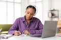 Diligent black lady student with headphones writing notes Royalty Free Stock Photo