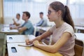 Diligent teenage girl studying in college with classmates