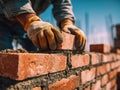 Construction worker wearing gloves carefully laying bricks with cement mortar on a sunny building site for a sturdy wall structure Royalty Free Stock Photo