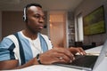 Diligent man working on laptop with headset on