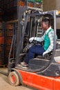 Confident African-American male forklift driver working in citrus fruit warehouse