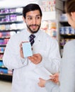 Male specialist is helping female client choose medicine in pharmacy.