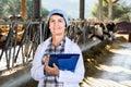 Female quality expert is standing in uniform and checking the quality of milk at the farm.