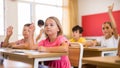 Diligent preteen schoolgirl raising hand to answer at lesson Royalty Free Stock Photo