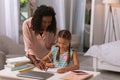 Positive smart little girl writing with mother Royalty Free Stock Photo