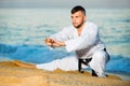 Man in uniform doing taekwondo exercises at sunset sea shore Royalty Free Stock Photo