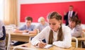 Diligent teenage girl studying in college with classmates