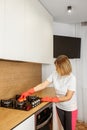 Woman in Red Gloves Cleaning Modern Gas Stove Royalty Free Stock Photo