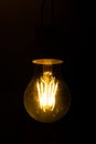 Dim light bulb on a black background. Gloomy black background. Old dirty lamp dimly lit for Halloween