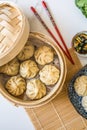 Dim sum aka dumplings,momos in a traditional bamboo steamer, with red chopsticks, Chinese cabbage Royalty Free Stock Photo
