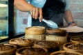 Dim sum in bamboo steamer chinese cuisine. close up woman female hands holding tongs choosing meal delicious food in wood basket Royalty Free Stock Photo