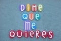 Dime que me quieres, tell me you love me, spanish text composed with multi colored stone letters over green sand