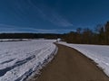 Paved agricultural road with snow-covered fields and bare trees in winter near Gundelfingen, MÃÂ¼nsingen, Germany.