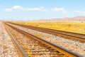 Diminishing perspective of railway tracks through flat plains of New Mexico with distant mesa landforms under blue sky Royalty Free Stock Photo