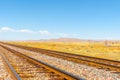 Diminishing perspective of railway tracks through flat plains of New Mexico with distant mesa landforms under blue sky Royalty Free Stock Photo