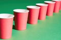 Diminishing perspective of red paper cup in row on green background