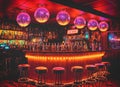 Dimly lit bar with neon lighting. The bar is decorated with several disco balls and displays a wide variety of liquor bottles. Royalty Free Stock Photo