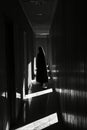 A dimly lit corridor with a solitary figure cloaked in shadows