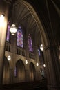 The dimly lit interior of the side of the Duke University Chapel with ornate architecture and stained glass windows