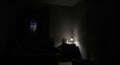 Dimly lit room with a lamp on a bedside table Royalty Free Stock Photo