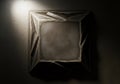 A dimly lit square artwork with intricate geometric patterns on a dark textured wall creates a Royalty Free Stock Photo