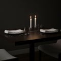 A dimly lit table setting with two white candles in holders providing warm light. It Royalty Free Stock Photo