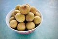 Longan in white bowl, placed on green background. Royalty Free Stock Photo