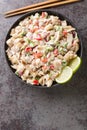 Dinakdakan Filipino appetizer of pig ears, face, brains with vegetables close-up in a bowl. Vertical top view