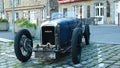 View on front of classic french Amilcar cabriolet car from the 30th with crank handle motor starter typical in village focus on c