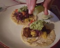 Diner squeezing lime juice onto fish tacos