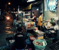 Diners eating at outdoor restaurant night at food stree