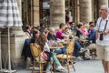 Diners relax at cafe tables in the sun under the columns of the