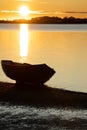 Dinghy in silhouette at waters edge in golden glow of rising sun