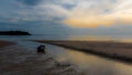 Dinghy sitting in tidal pool at beach at low tide during sunset with anchor trailing behind