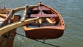 Dinghy, small rowing boat, made of mahogany wood, attached to the stern of a vintage sailing yacht. Schleswig-Holstein, Germany