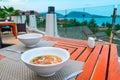 Dining concept on the open-air terrace on the ocean side. Deep white ceramic soup plates on bamboo mats and vintage wooden table.