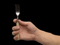 Dining fork in hand on a black background Royalty Free Stock Photo