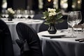 A dining hall is adorned with black chair covers and laid tables, flowers for a formal event. The serene mood reflects a Royalty Free Stock Photo