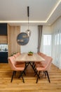 Dining room with a sleek wooden table surrounded by modern pink chairs Royalty Free Stock Photo