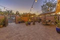 Dining and seating area on a stone brick patio illuminated by string lights