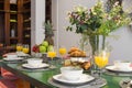 Dining table with breakfast service, juices, fruits and pastries ready
