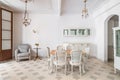 Dining table in a center of living room decorated in retro style. Tile floor and vintage chandeliers in refurbished