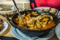 On the dining table is a hot pan with Seafood stew - Zarzuela. horizontal view, closeup. Selective center focus and blurred