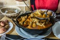 On the dining table is a hot pan with Seafood stew - Zarzuela. horizontal view, closeup. Selective center focus and blurred