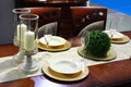 Dining table with modern decorative chairs, candlesticks, dishes and glasses, some artificial plant on right side