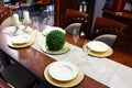 Dining table with modern decorative chairs, candlesticks, dishes and glasses, some artificial plant on right side